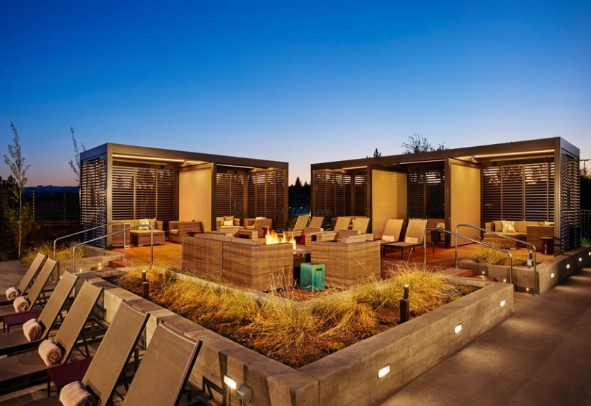 Pergolas line a seating area with a fire pit at dusk