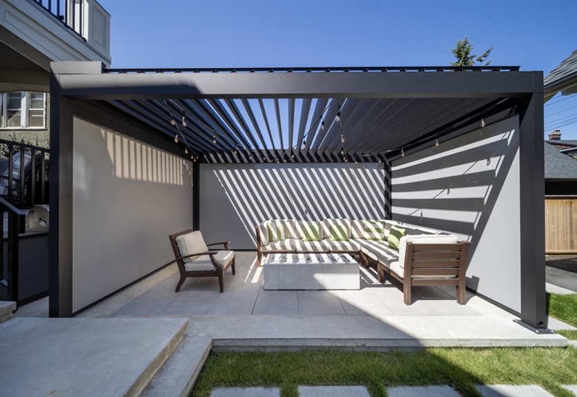 Black louvered pergola in a private backyard enclosed with 3 motorized outdoor screens