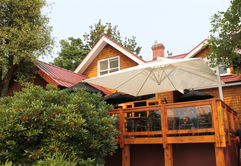 A beige umbrella shades a wood deck