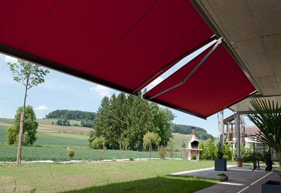 Red arm bracket awning open over a home patio space