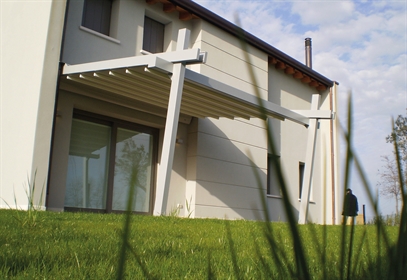 A simple white pvc retractable pergola that is wall mounted to a white home