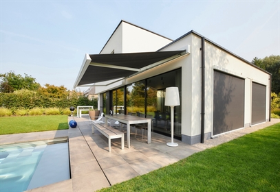 Contemporary backyard with sleek awning providing shade over outdoor patio