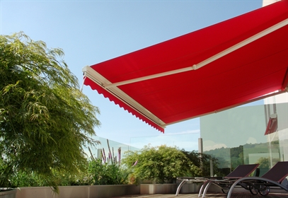 Red arm bracket open over chaise lounge chairs on an apartment patio
