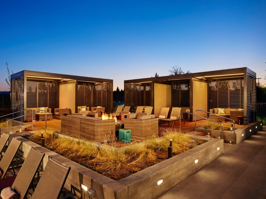 Pergolas line a seating area with fire pit at dusk