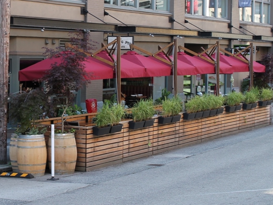 cantilevered red umbrellas on a curbside patio