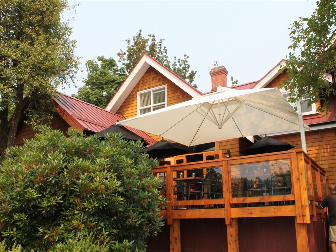 A beige umbrella shades a wood deck