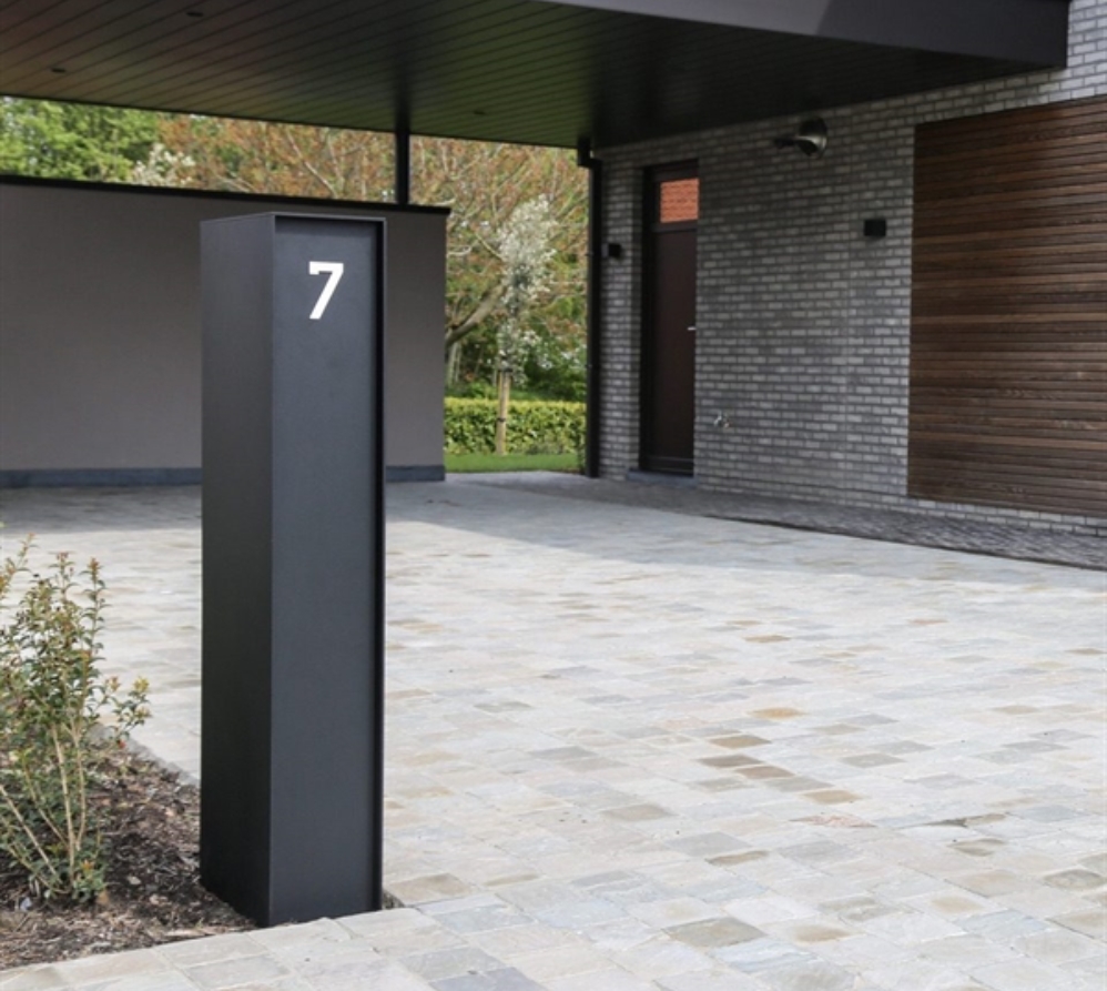 black vertical box mailbox with custom number in silver integrated installed in a garden