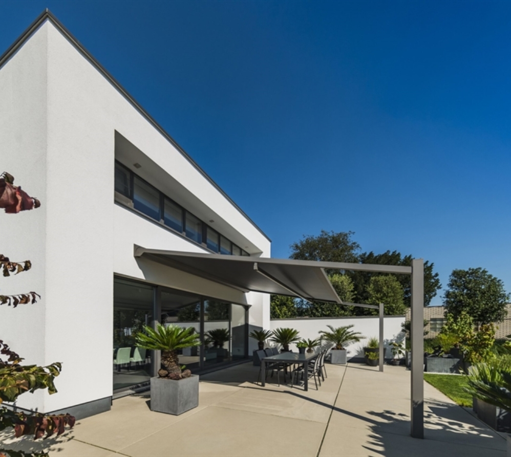 Modern patio with retractable awning wall mounted to home and outdoor dining area