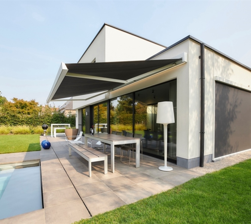 Black coloured awning over dining set on stone patio.